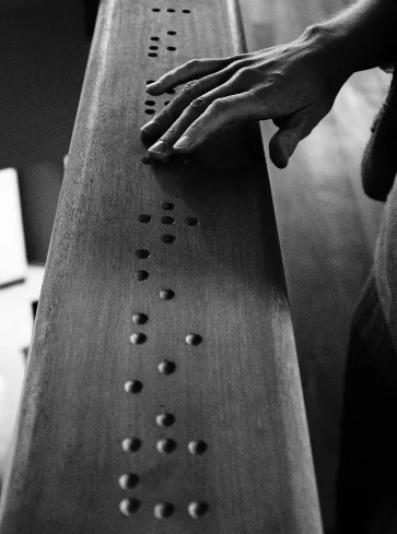 Schwarz-Weiß-Foto: eine Hand tastet erhabene Braille-Punkte